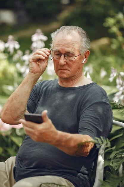 Concept de technologie, de personnes et de communication. Man au parc d'été. Grangfather utilisant un téléphone.