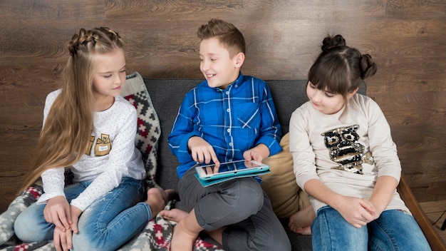 Concept de technologie avec trois enfants sur le canapé