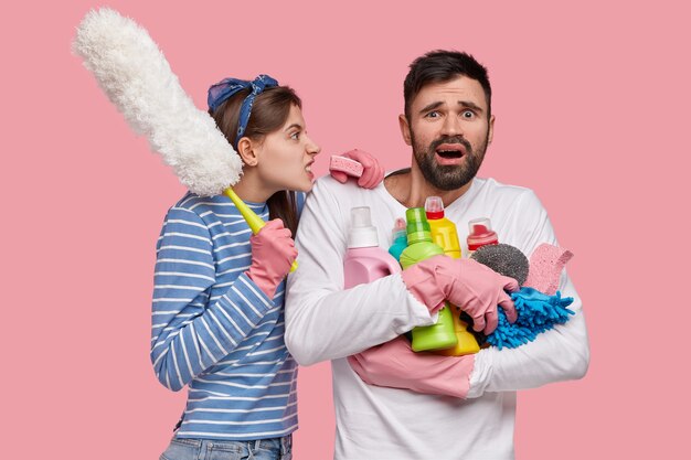 Concept de travail domestique et de relations. Une jeune femme irritée et mécontente crie avec colère à son mari paresseux