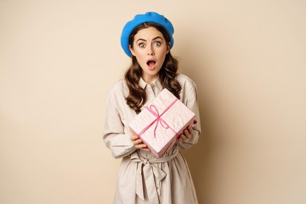 Concept de vacances et de cadeaux belle femme tenant une boîte-cadeau avec un visage d'incrédulité surpris recevoir gi...