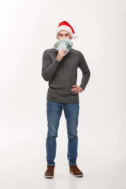 Concept de vacances jeune homme barbe tenant de l'argent devant sur fond blanc