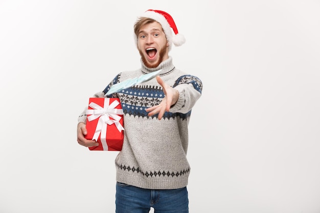 Concept de vacances Jeune homme barbe tenant un cadeau de Noël et jetant de l'argent à la caméra