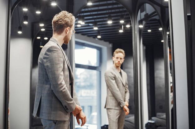 Concept de vente, de shopping, de mode, de style et de personnes. Jeune homme élégant choisissant des vêtements dans un centre commercial ou un magasin de vêtements.