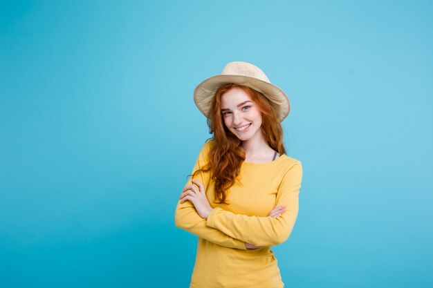 Concept de voyage - Close up Portrait jeune belle fille sexy redhair avec un chapeau à la mode et des lunettes de soleil souriantes. Blue Pastel Background. Espace de copie.