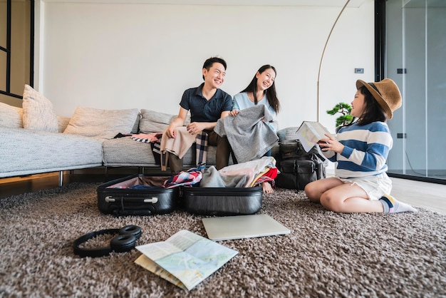 Concept de voyage en famille asiatique bonheur papa maman fille chiffons d'emballage et de rabotage pour les vacances road trip avec excité et joyeux