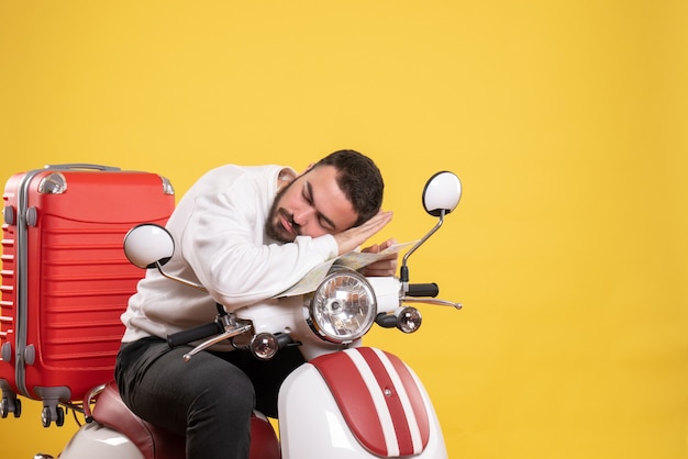 Concept de voyage avec un gars endormi assis sur une moto avec une valise dessus en jaune