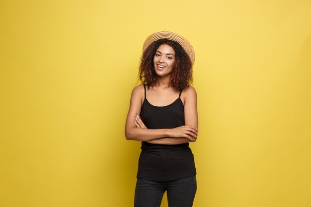 Concept de voyage - Gros plan Portrait jeune et belle femme afro-américaine attrayante avec un sourire à la mode et une expression joyeuse. Fond d&#39;écran en pastel jaune pastel. Espace de copie.