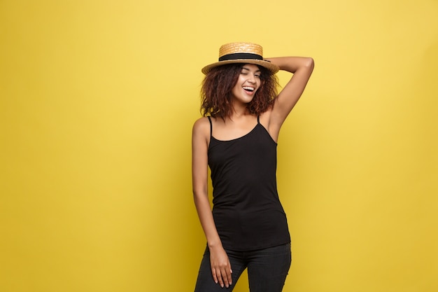 Concept de voyage - Gros plan Portrait jeune et belle femme afro-américaine attrayante avec un sourire à la mode et une expression joyeuse. Fond d&#39;écran en pastel jaune pastel. Espace de copie.