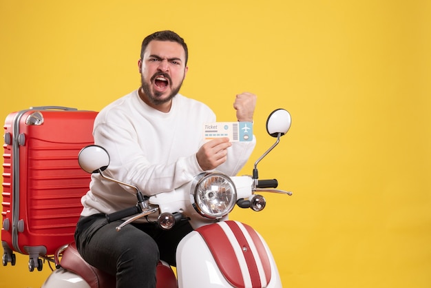 Concept de voyage avec un homme ambitieux et émotionnel assis sur une moto avec une valise dessus montrant un billet en jaune