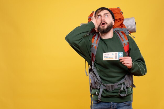 Concept de voyage avec jeune homme concentré avec packpack et billet montrant sur jaune