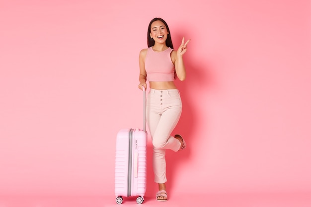 Concept de voyage, vacances et vacances. Joyeuse fille asiatique en vêtements d'été sacs emballés pour voyager à l'étranger