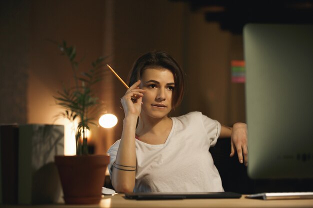 Concepteur de jeune femme concentré tenant un crayon.