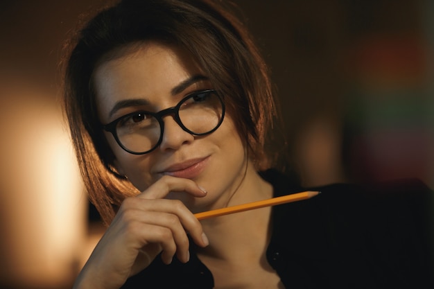 Concepteur de jeune femme concentré tenant un crayon.