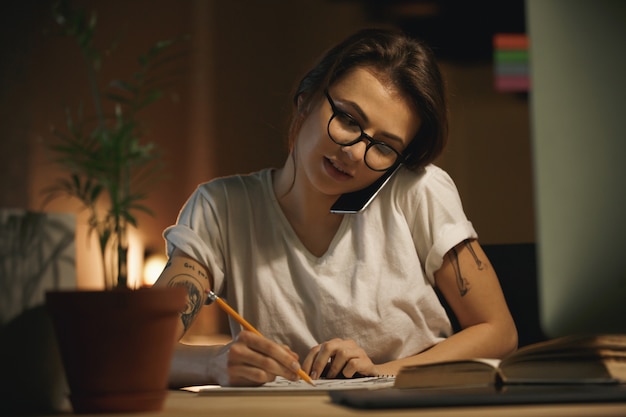 Concepteur de jeune femme concentrée parler par téléphone mobile