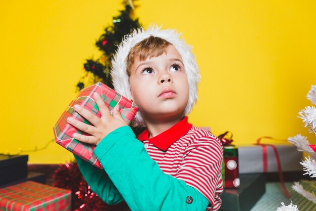 Concepto de Noël avec garçon secouant la boîte présente