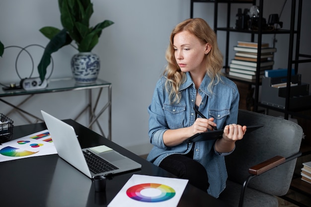 Conceptrice de logo féminin travaillant dans son bureau sur une tablette graphique