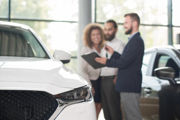 Concessionnaire automobile discutant de l'achat d'une voiture avec des clients