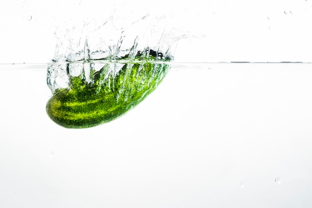 Concombre entier vert éclabousser dans l&#39;eau propre sur fond blanc