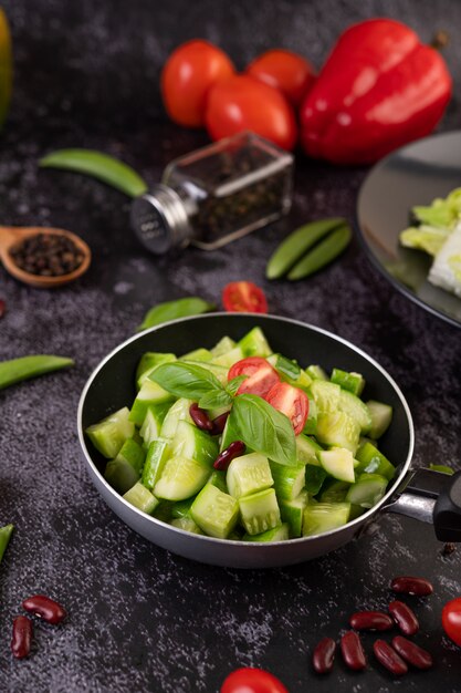 Concombre sauté aux tomates et haricots rouges dans une poêle.