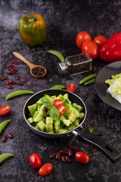 Concombre sauté aux tomates et haricots rouges dans une poêle.