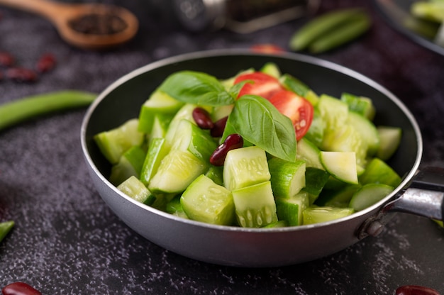 Concombre sauté aux tomates et haricots rouges dans une poêle.