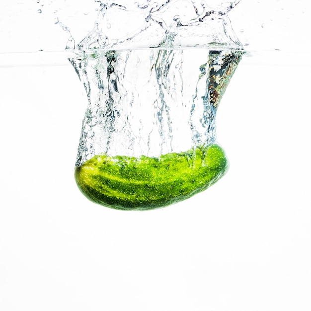Photo gratuite concombre tombant dans l'eau avec des éclaboussures d'eau sur fond blanc