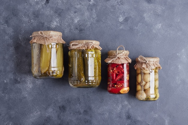 Photo gratuite concombres marinés, olives et poivrons rouges dans des bocaux en verre sur fond bleu.