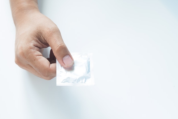 Condom dans la main masculine sur fond blanc