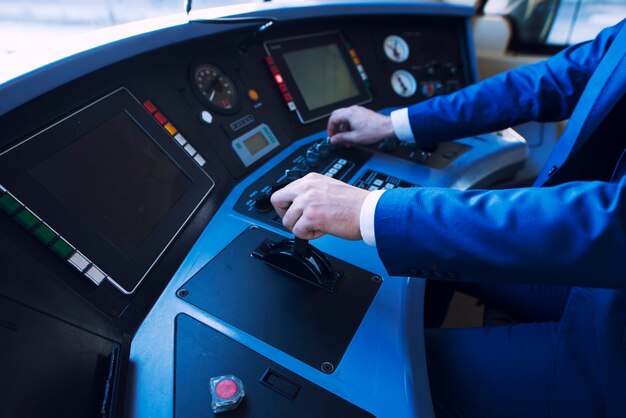 Conducteur professionnel en uniforme opérant dans le cockpit du train et conduisant un train à grande vitesse