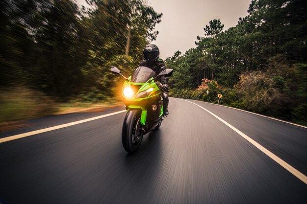 Conduire une moto de couleur néon verte sur la route au crépuscule.