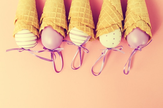 Cones De Glace Colorés Aux Oeufs De Pâques Sur Fond Rose. Vanille Ou Pastel Toning. Minimalisme. Flat Lay.