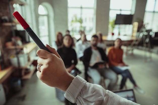 Photo gratuite conférencière musulmane faisant une présentation dans le hall de l'atelier. salle d'audience ou de conférence. gros plan sur la main pointée avec un marqueur. conférence événement, formation. éducation, diversité, concept inclusif.