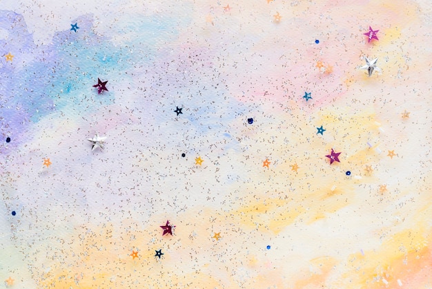 Confettis étoiles pailletées sur fond aquarelle pastel abstrait coloré