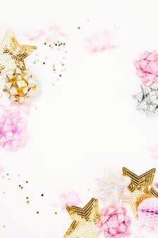 Confettis rose pastel, nœuds et décorations en papier. mise à plat, vue de dessus. composition de vacances pour fête d'anniversaire, célébration du nouvel an/noël ou thème de concept de fête de poule. mise à plat, vue de dessus