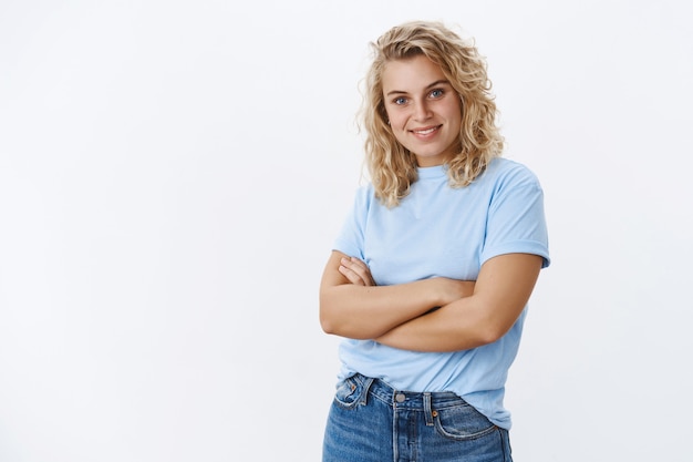 Confiance pour les dirigeants. Portrait d'une belle femme blonde affirmée et confiante aux yeux bleus souriante, sûre d'elle et optimiste alors que les mains croisées sur le corps, souriant assurées du succès