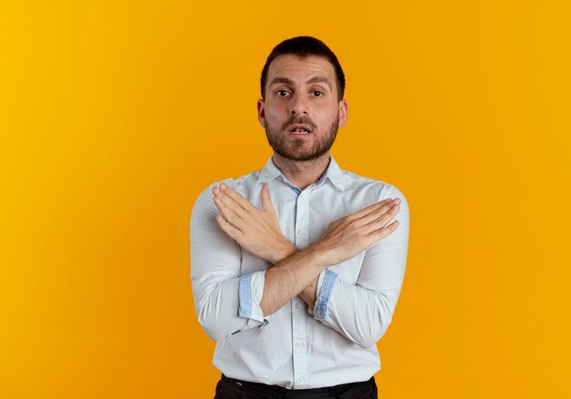 Confiant bel homme croise les mains ne faisant aucun signe isolé sur un mur orange