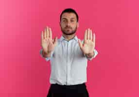 Photo gratuite confiant bel homme gestes arrêt signe de la main avec deux mains isolé sur mur rose