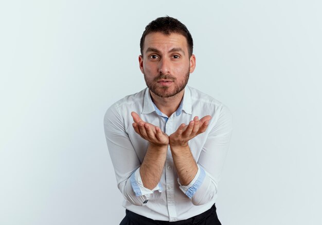 Confiant bel homme tient les mains ensemble à la recherche d'isolement sur le mur blanc