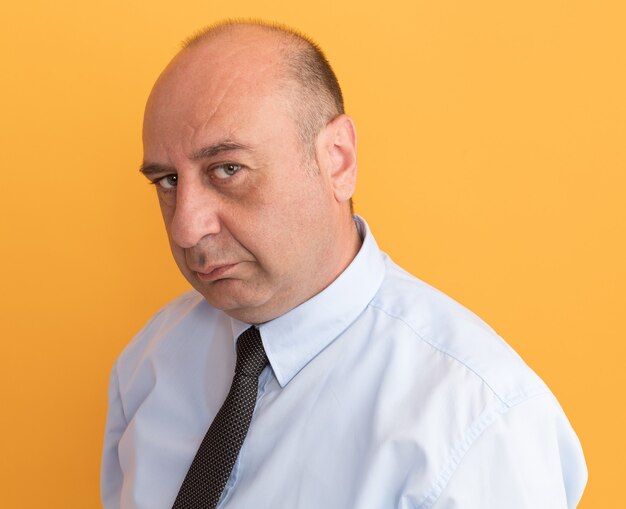 Confiant homme d'âge moyen portant un t-shirt blanc avec cravate isolé sur mur orange