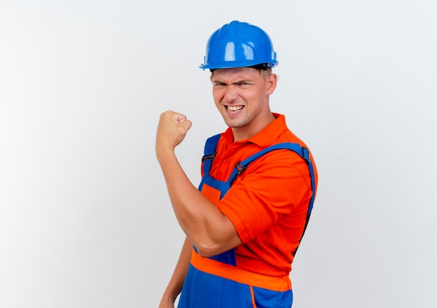 Confiant jeune constructeur masculin portant l'uniforme et un casque de sécurité faisant un geste fort