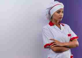 Photo gratuite confiant jeune femme cuisinier portant l'uniforme de chef tenant un mur blanc croisant les mains sur un mur isolé avec espace copie