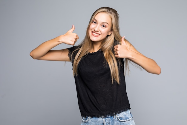 Confiant jeune femme donnant les pouces vers le haut sur un fond gris