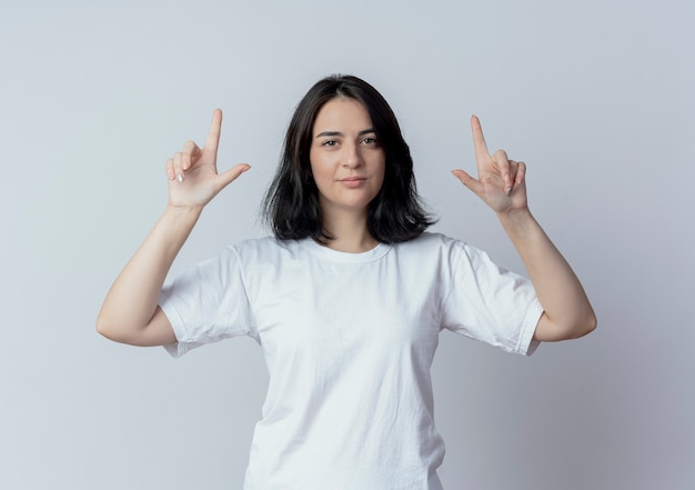 Confiant jeune fille assez caucasienne pointant avec les doigts vers le haut isolé sur fond blanc