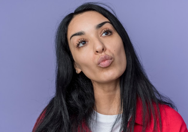 Confiant jeune fille de race blanche brune regarde à côté isolé sur mur violet