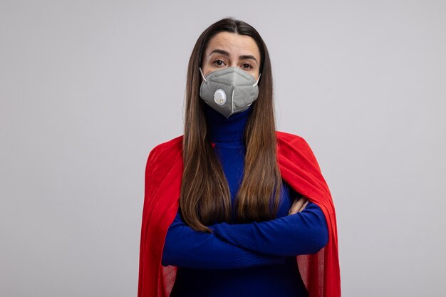 Confiant jeune fille de super-héros portant un masque médical croisant les mains isolés sur blanc
