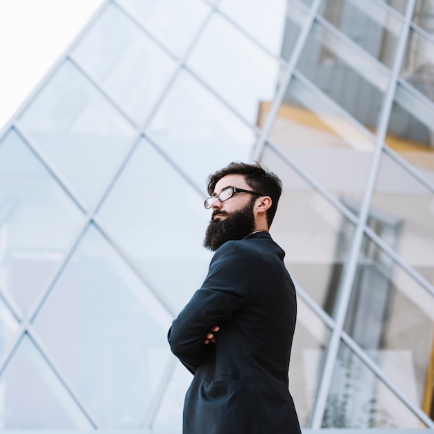 Confiant, jeune homme affaires, debout, devant, bâtiment verre