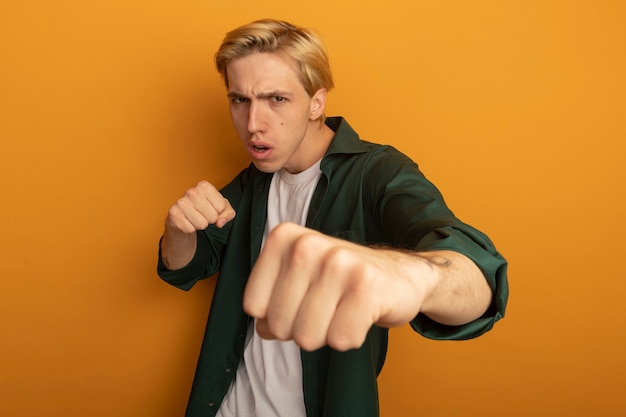 Photo gratuite confiant jeune homme blond vêtu d'un t-shirt vert pose de combat debout