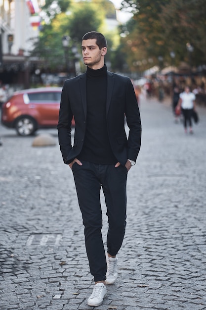 Confiant jeune homme marchant dans une rue de la ville européenne