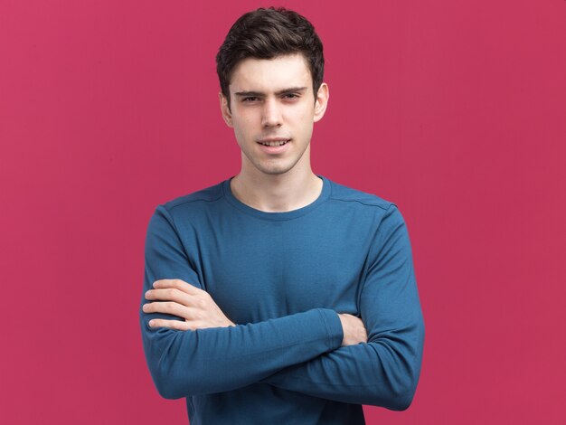 Confiant jeune homme de race blanche brune se tient les bras croisés isolés sur le mur rose avec espace de copie