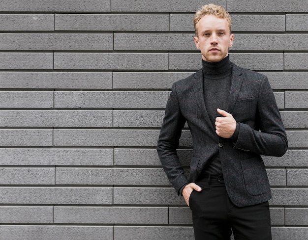 Confiant jeune homme avec sa main dans la poche sur fond gris